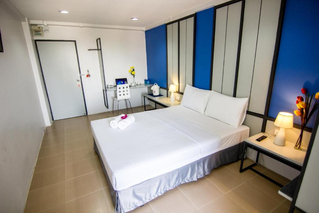 暖武里府Regent Ngamwongwan Hotel的蓝色墙壁的房间里一张大白色的床