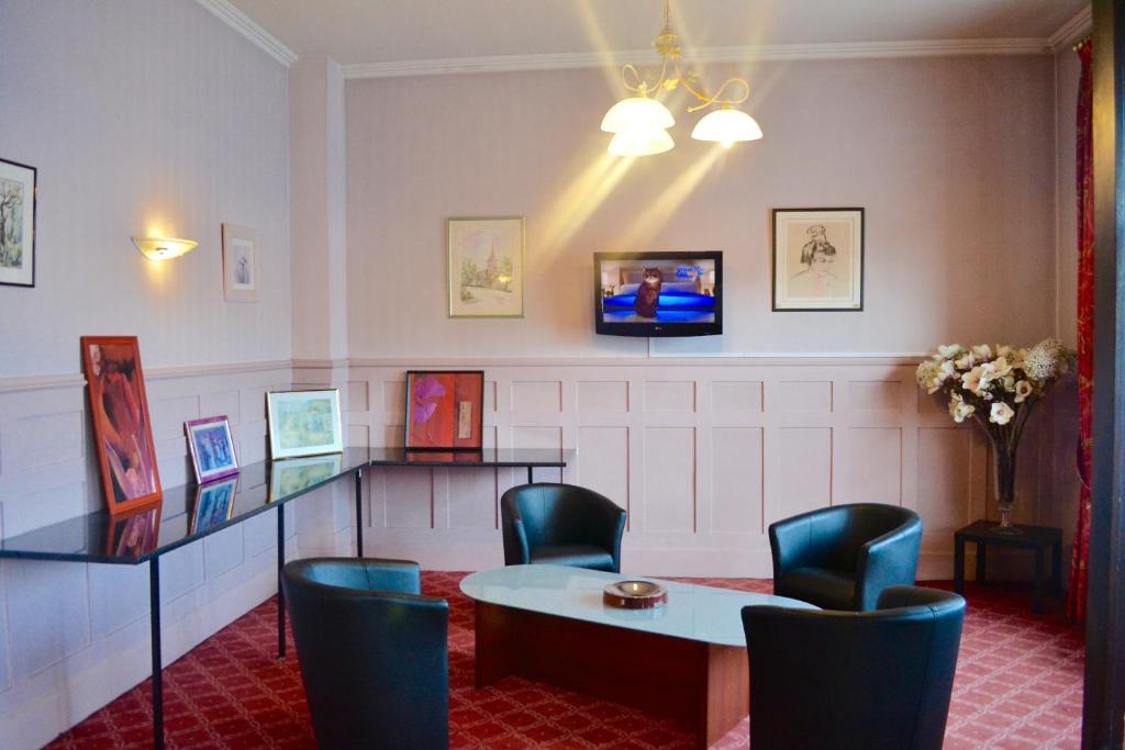 埃夫勒格兰德酒店的一间设有桌椅和电视的等候室
