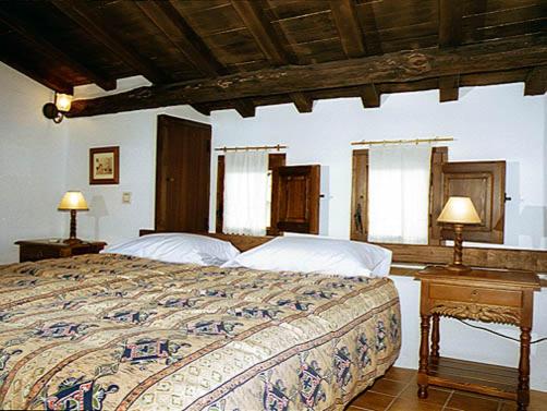 Casas del CastañarCasa Rural La Cueva的一间卧室配有一张带两张台灯的床。