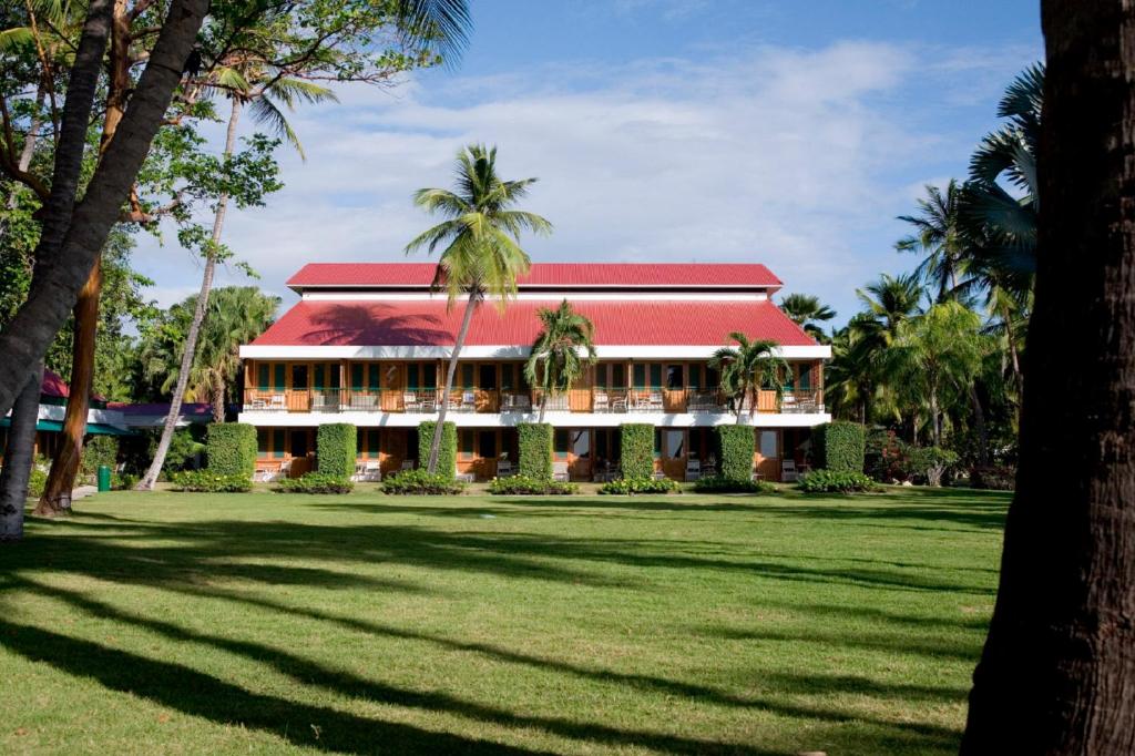 瓜尼卡克帕玛丽娜海滩温泉度假村的一座红色屋顶和棕榈树的建筑