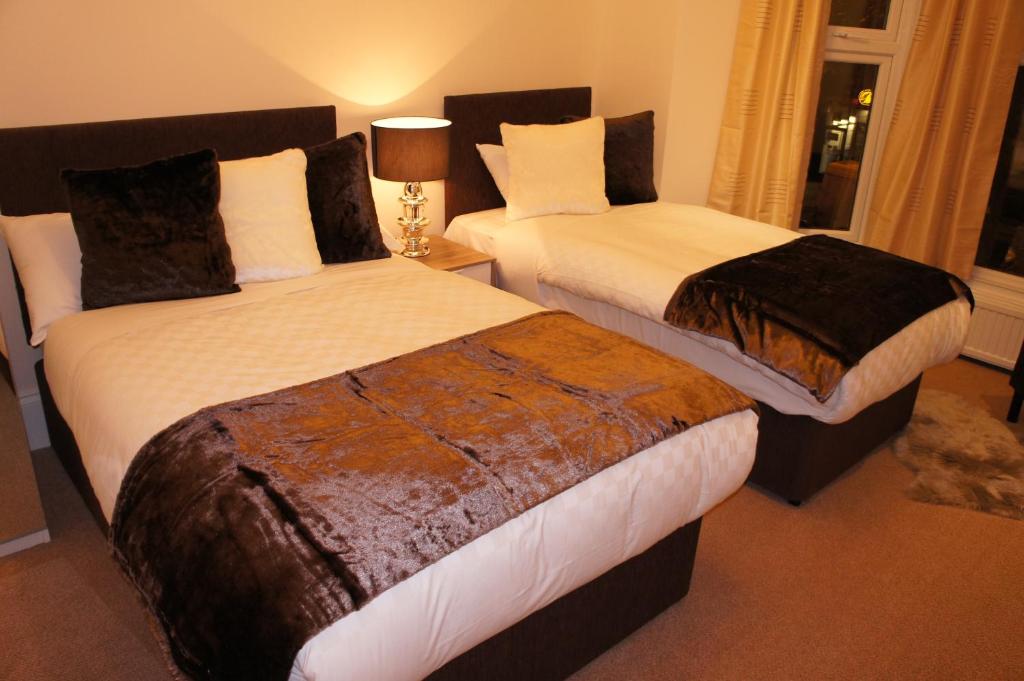 伦敦伦敦蓝宝石酒店的配有衬衫的酒店客房内的两张床