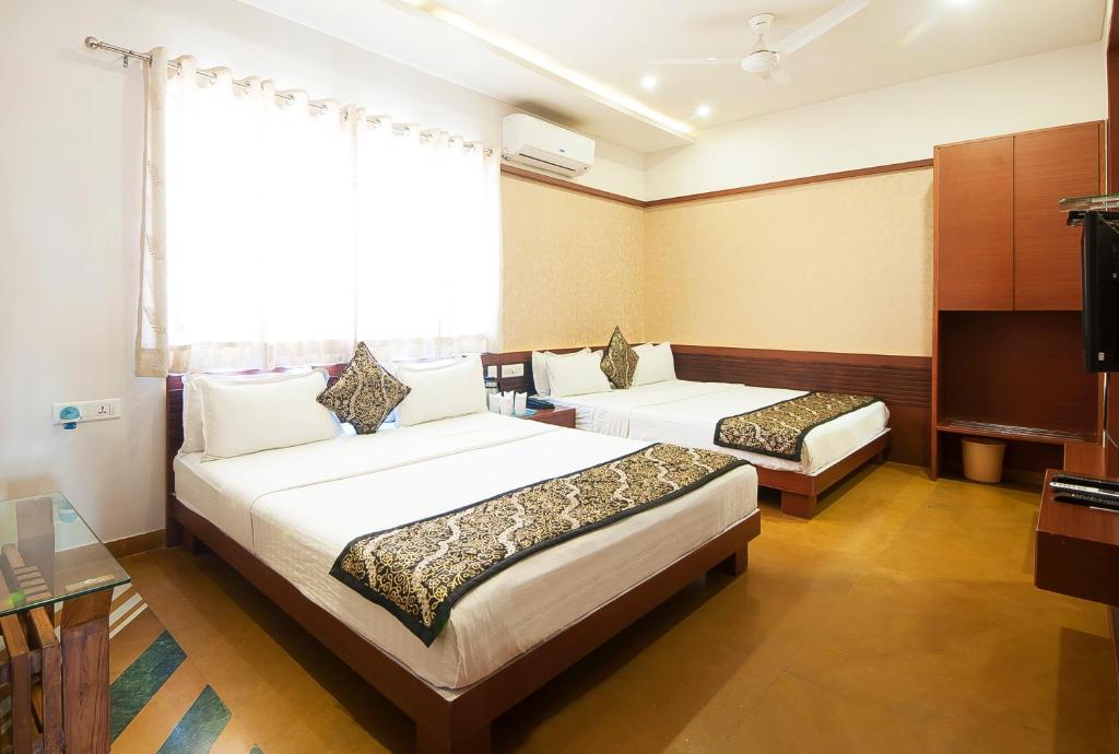 乌代浦Uddhav Vilas A Family Hotel的酒店客房设有两张床和一台平面电视。