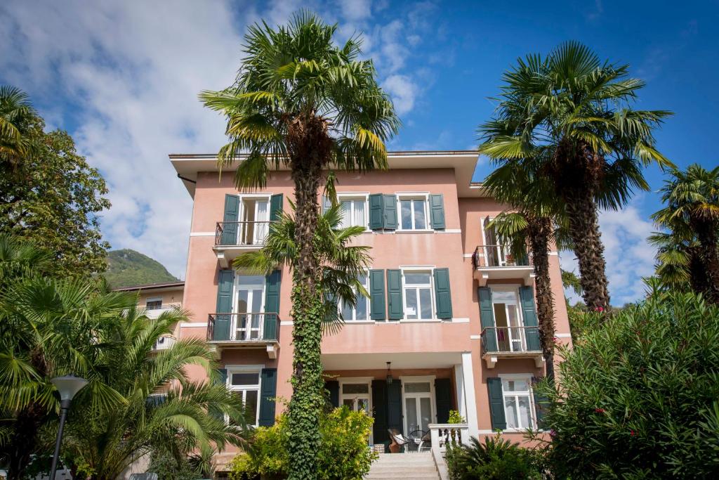 加尔达湖滨埃尔伯格加尔尼莫雷蒂别墅酒店的前面有棕榈树的粉红色建筑