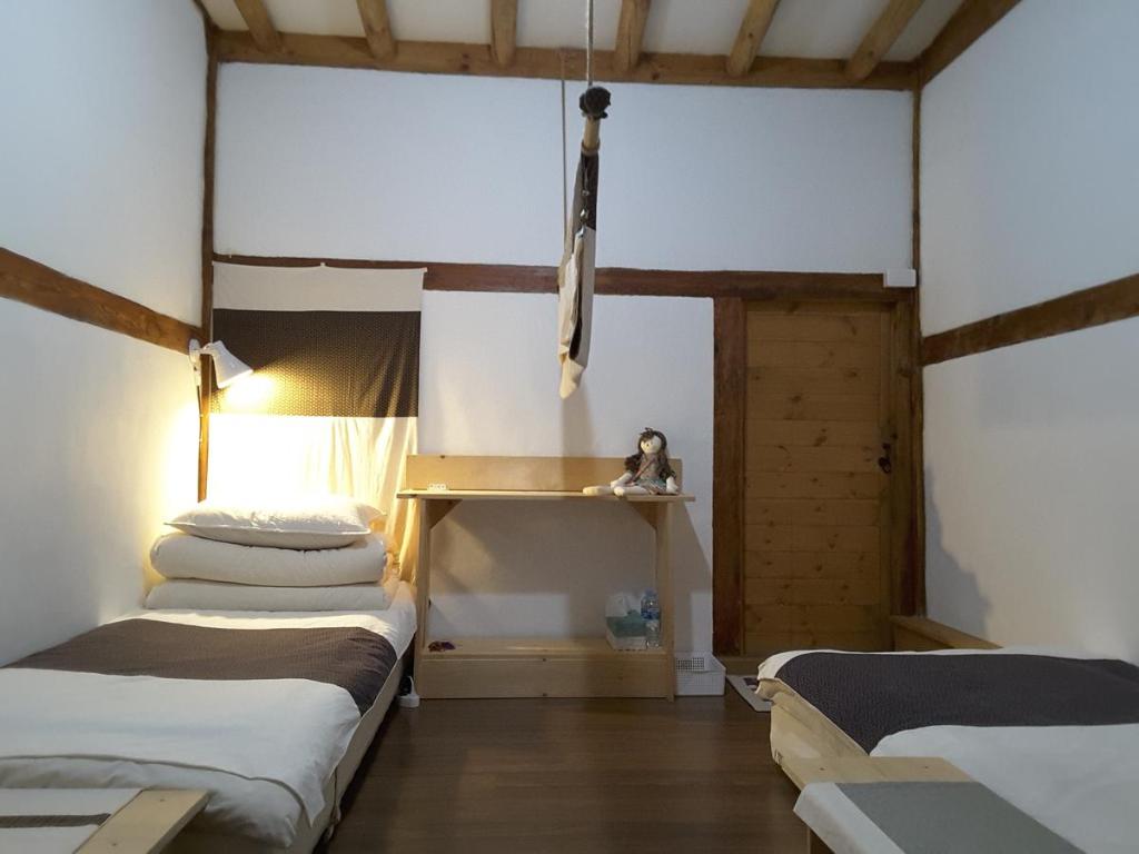 庆州耶陶尔韩屋旅馆的一间设有两张床的房间,其中有一个架子