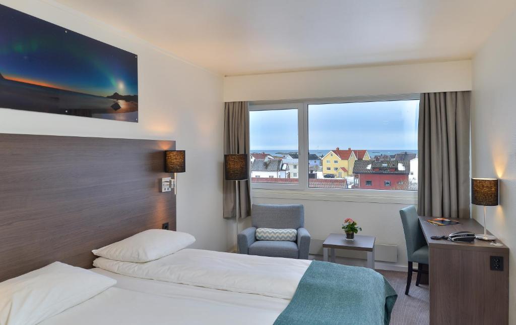 安德内斯Thon Partner Hotel Andrikken的酒店客房设有两张床、一张书桌和一个窗户。