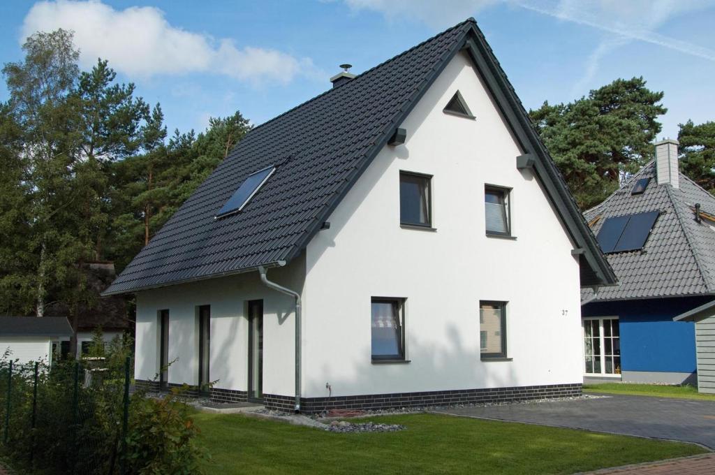 格洛韦Dünenresidenz Glowe - Haus Emily的黑色屋顶的白色房子