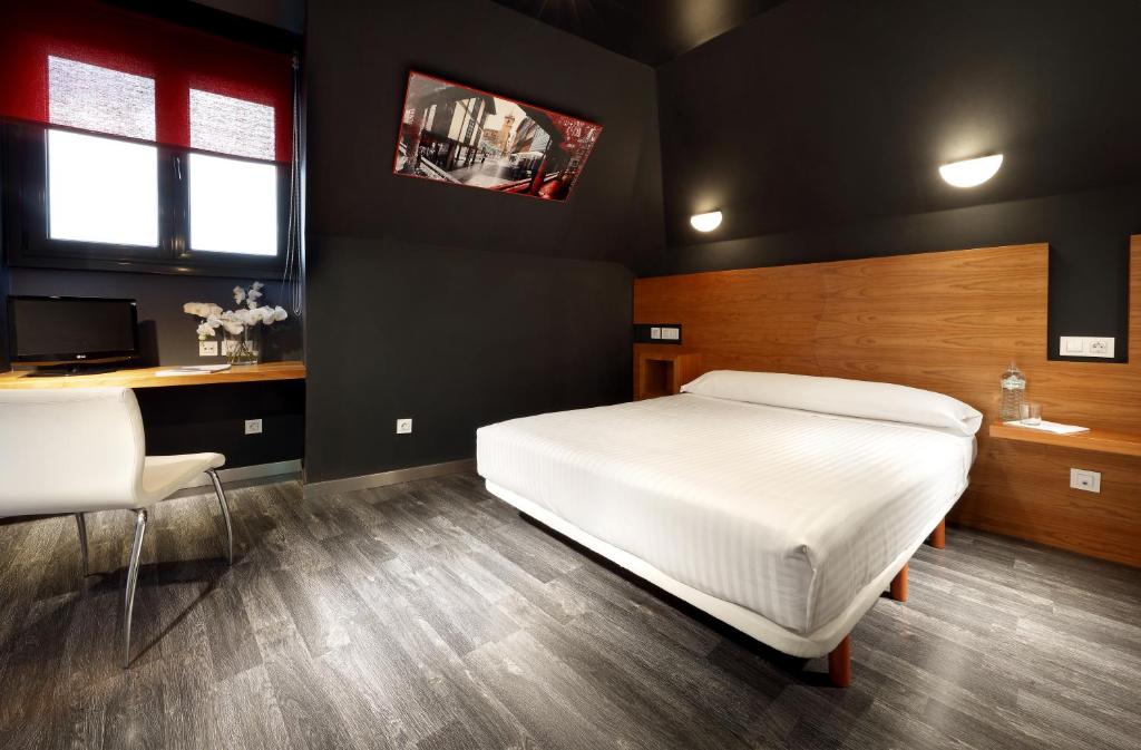 奥维多埃玛奇斯桃酒店的卧室配有白色的床、书桌和电视。