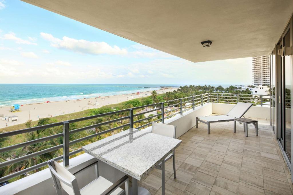迈阿密海滩Hilton Bentley Miami South Beach的配有桌椅的阳台，可欣赏海滩美景