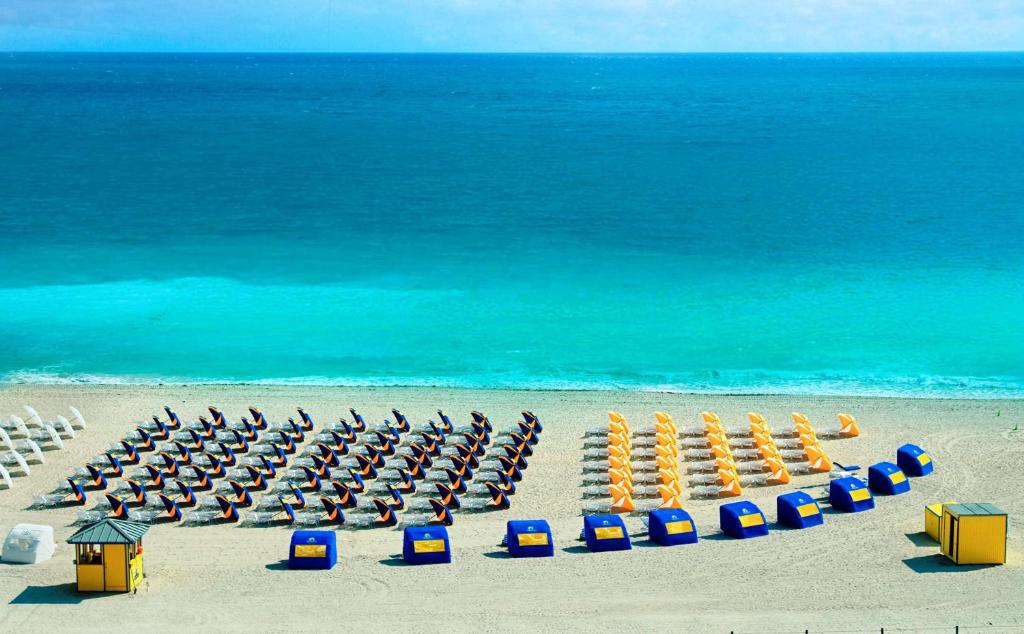 迈阿密海滩Hilton Bentley Miami South Beach的有椅子、遮阳伞和大海的海滩