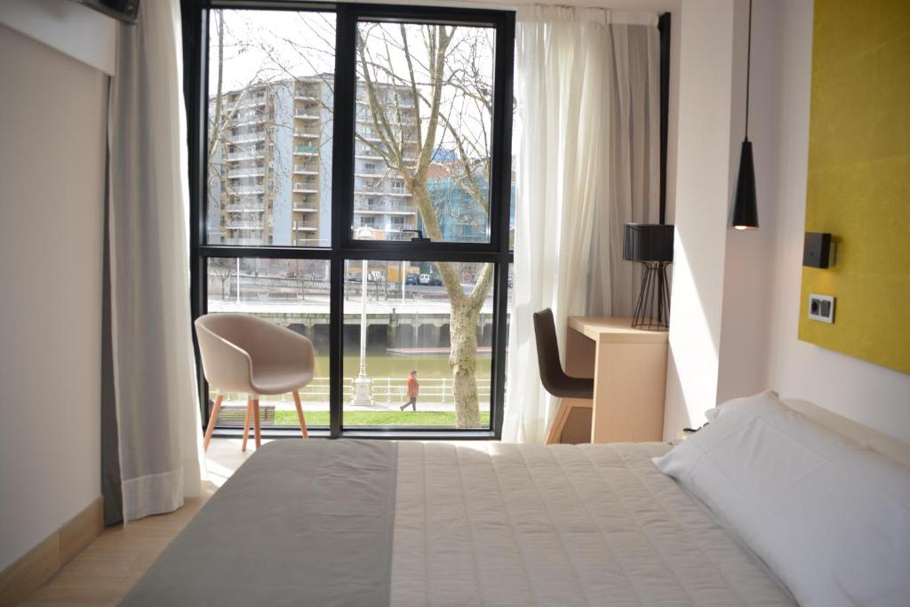 毕尔巴鄂毕尔巴鄂广场酒店的一间卧室设有一张床和一个大窗户