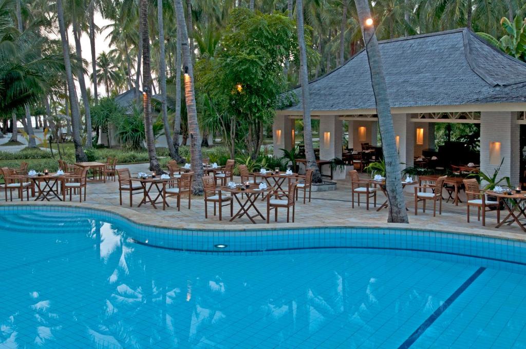 卡里蒙贾瓦库拉库拉度假酒店的一个带桌椅的游泳池以及一间餐厅