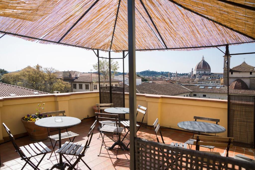 佛罗伦萨全景酒店的阳台配有桌椅和雨伞。