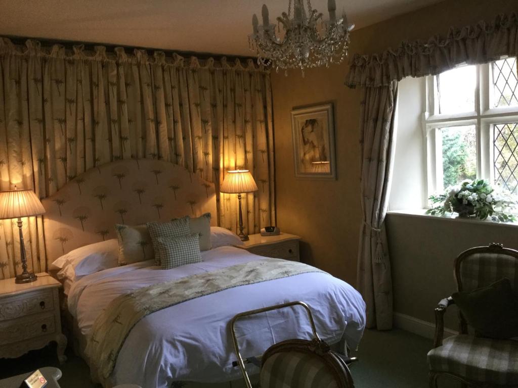 格兰瑟姆The Brownlow Arms Inn的一间卧室配有一张床、一个吊灯和一扇窗户