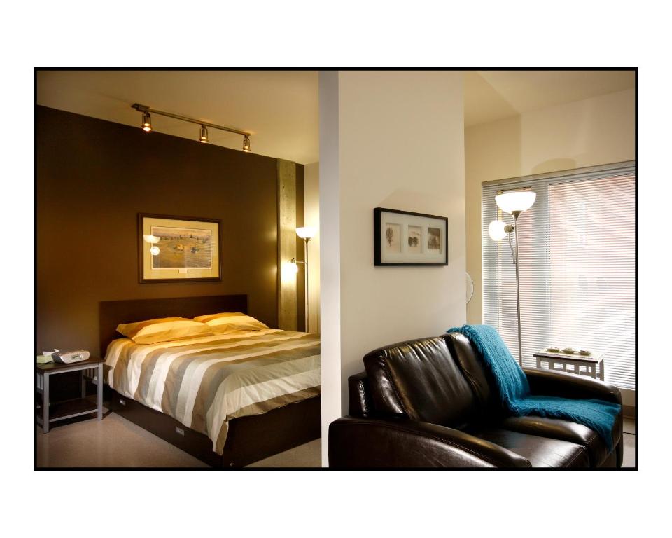 魁北克市魁北克大学公寓的一间卧室配有一张床和一张皮椅