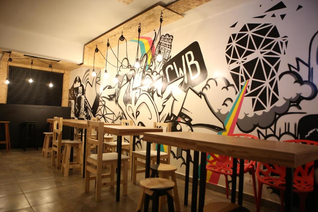 库里提巴Social Hostel Café e Bar的一间设有桌椅的房间和一堵涂鸦墙