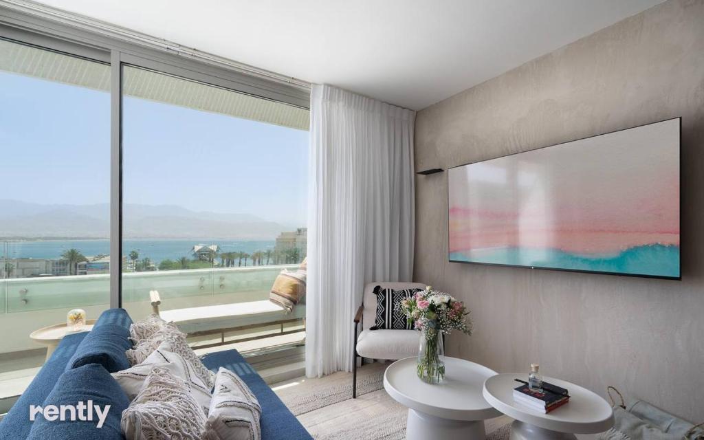 埃拉特Luxury Apartments And Studios At Sea Side By Rently的客厅设有蓝色的沙发和大窗户