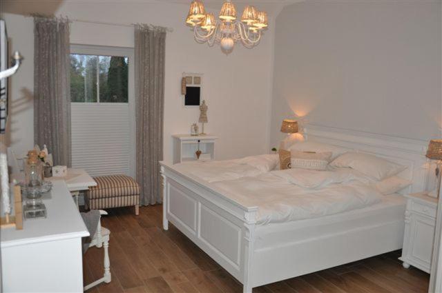 克洛彭堡White Cottage Garden的卧室配有白色的床和吊灯。