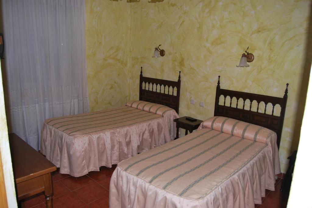 阿维拉贝拉斯旅馆的黄色壁纸客房内的两张床