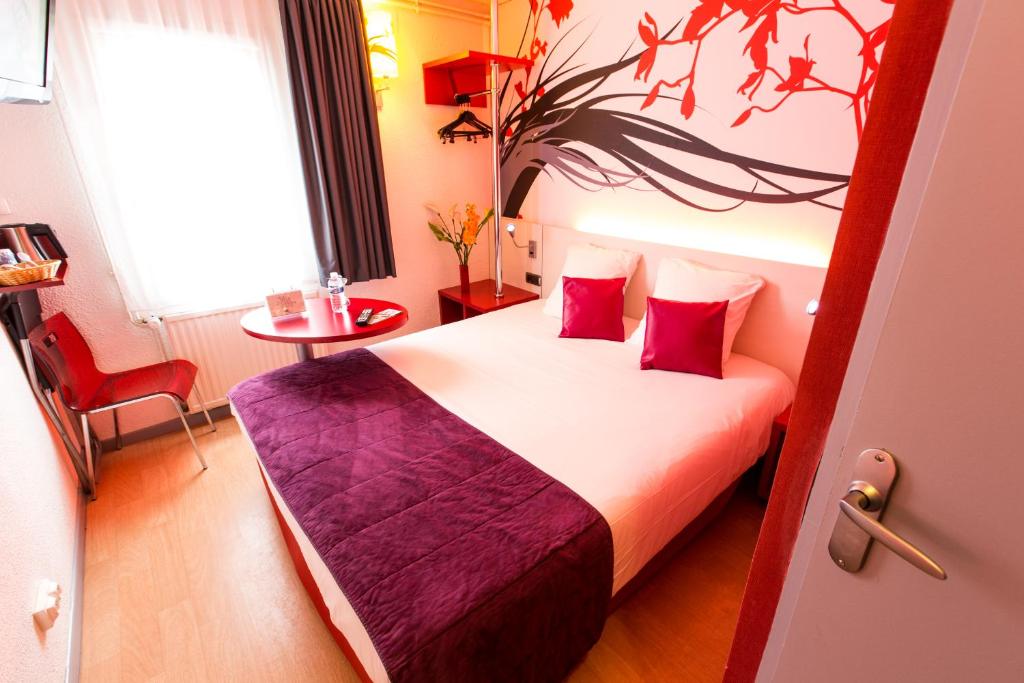 色当Hotel Inn Design Sedan的配有红色枕头的床的酒店客房