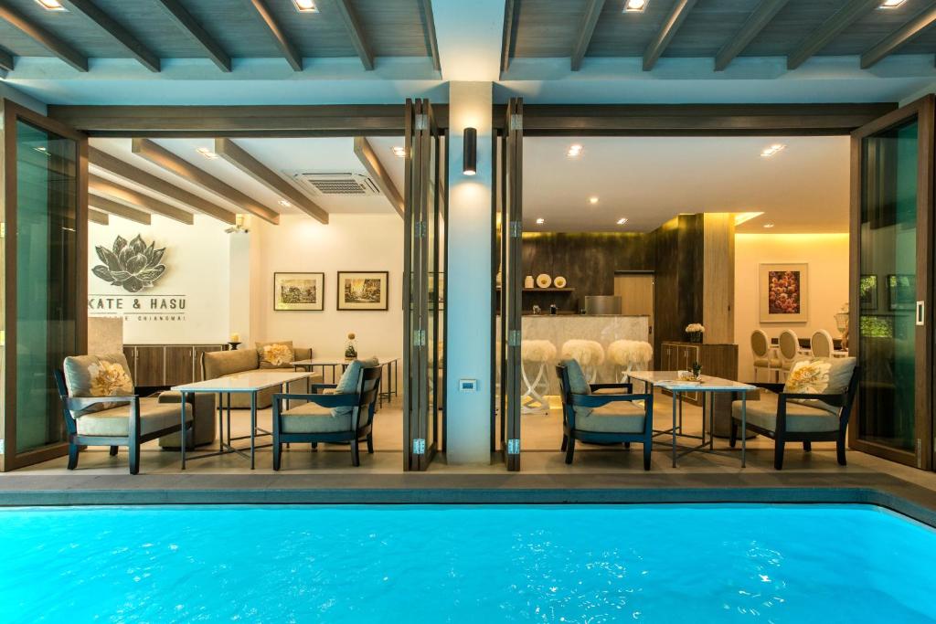 清迈凯特哈苏清迈精品酒店的用餐室前的游泳池,配有桌椅