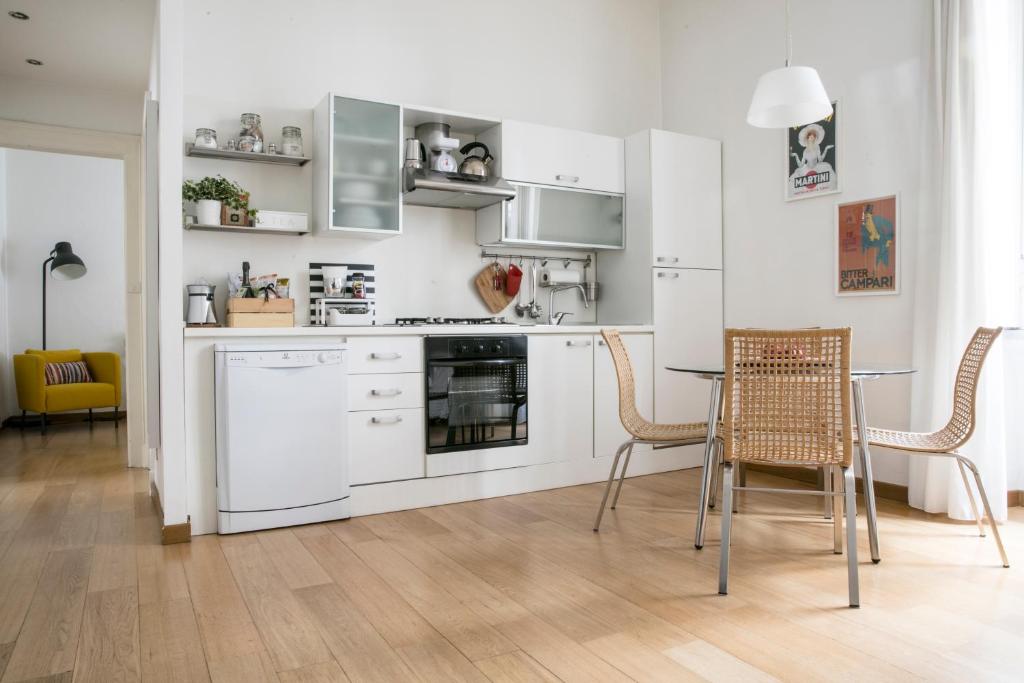 米兰洛弗蕾森皮昂奈公寓的厨房配有白色橱柜和桌椅