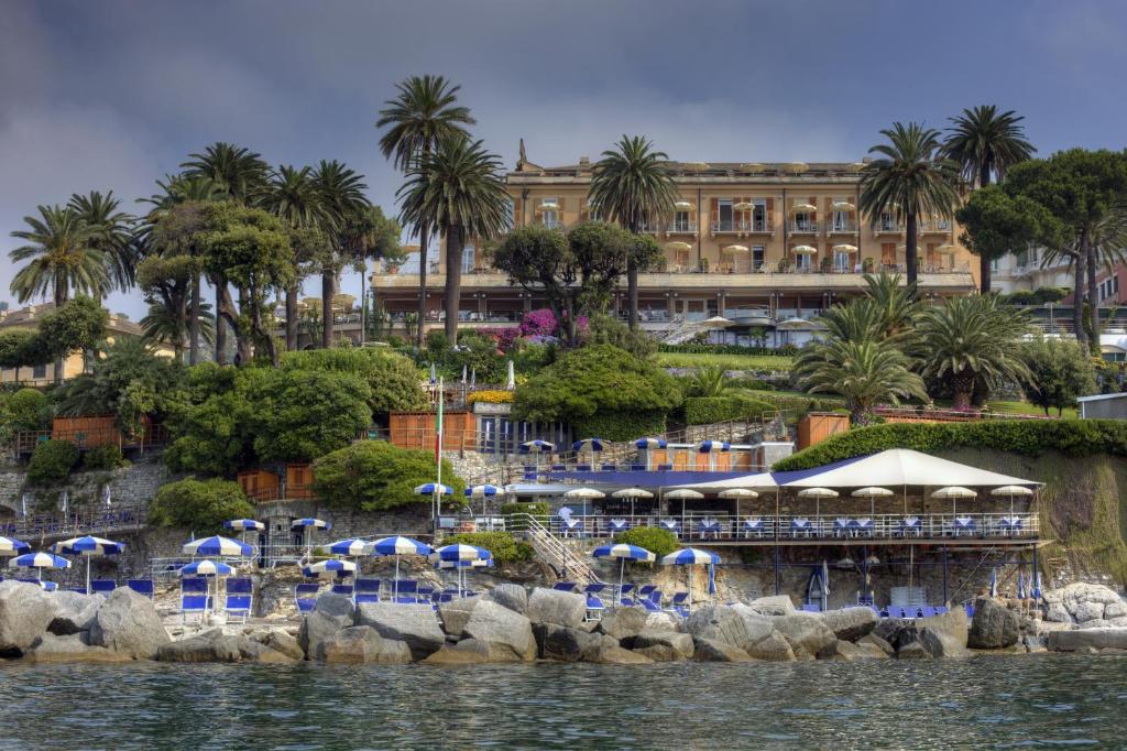 圣玛格丽塔-利古雷欧陆酒店的一个带椅子和遮阳伞的度假胜地和一座建筑