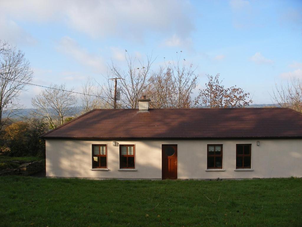 MountshannonMountshannon cottage的一间白色的小房子,有棕色的屋顶