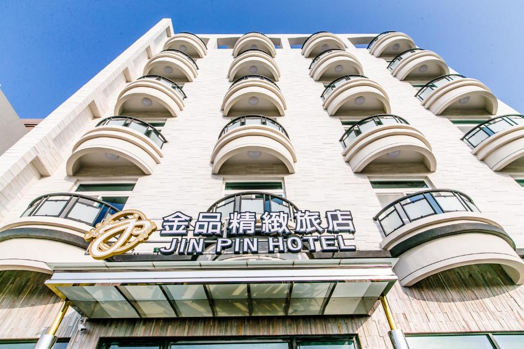 马公金品精致旅店的一座高大的白色建筑,上面有金银牌酒店标志