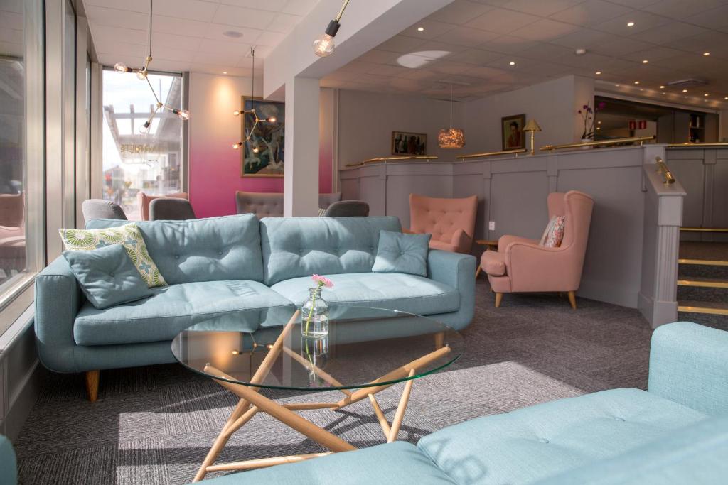 于默奥德拉格尼恩第一酒店的客厅配有蓝色的沙发和粉红色的椅子