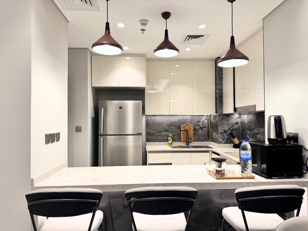 迪拜CaiCai Homes 1 BHK Nobles Tower Business Bay 5 min Drive to Dubai Mall的厨房配有带椅子的柜台和冰箱。