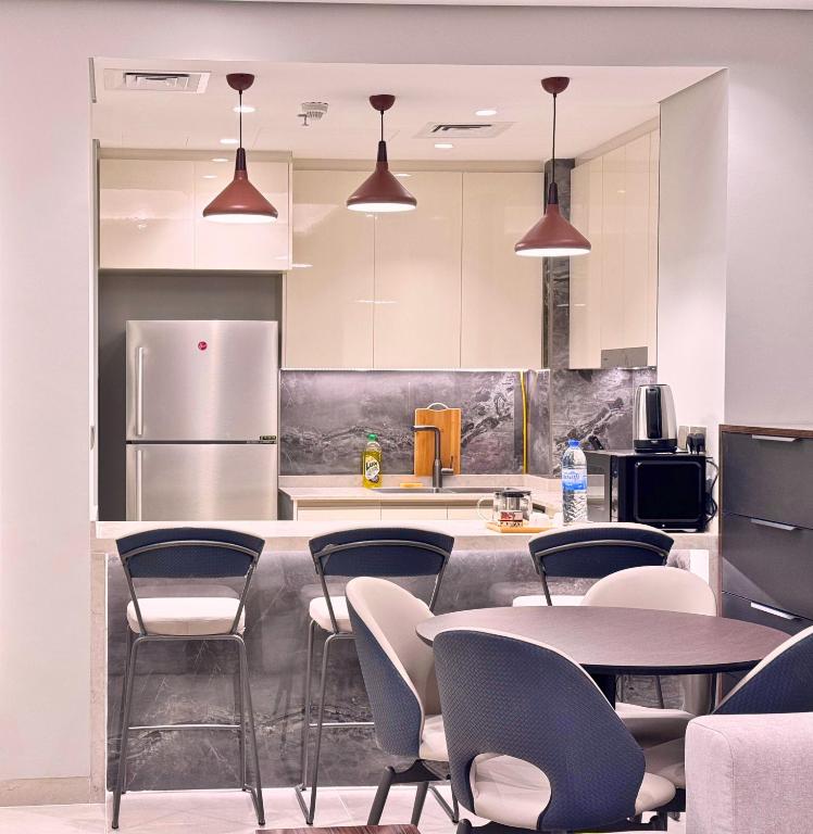 迪拜CaiCai Homes 1 BHK Nobles Tower Business Bay 5 min Drive to Dubai Mall的厨房配有桌椅和冰箱。