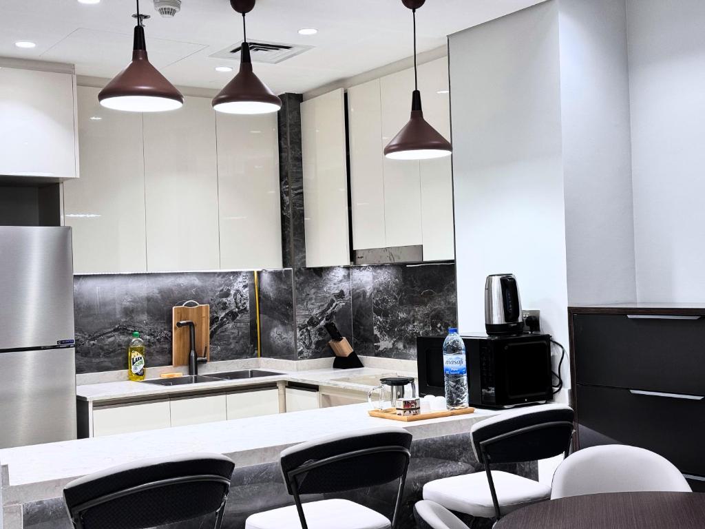 迪拜CaiCai Homes 1 BHK Nobles Tower Business Bay 5 min Drive to Dubai Mall的厨房配有白色橱柜和黑白电器