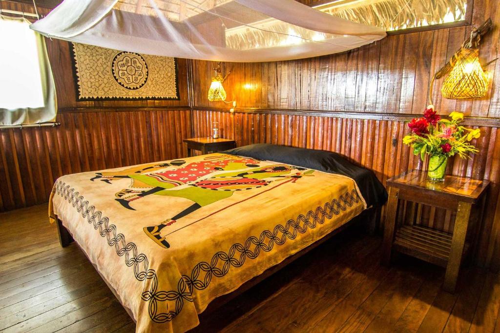 马尔多纳多港Corto Maltes Amazonia Lodge的一间卧室配有一张床和一张鲜花桌