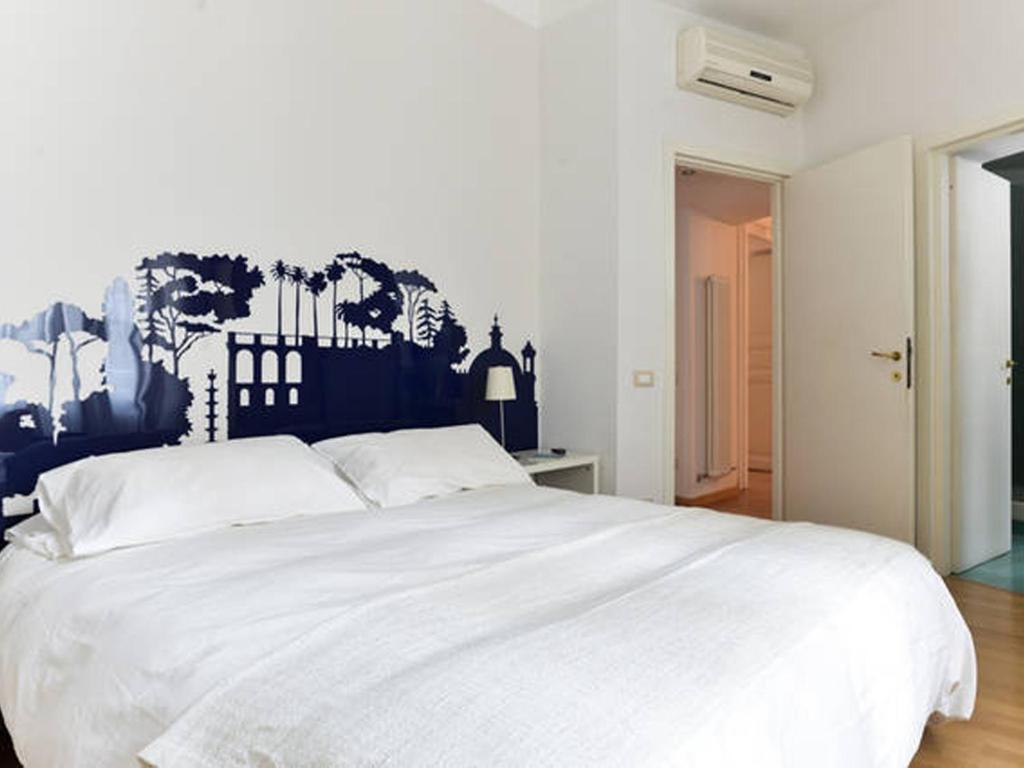 罗马维亚德洛卡35号公寓的卧室配有白色床,墙上挂有壁画