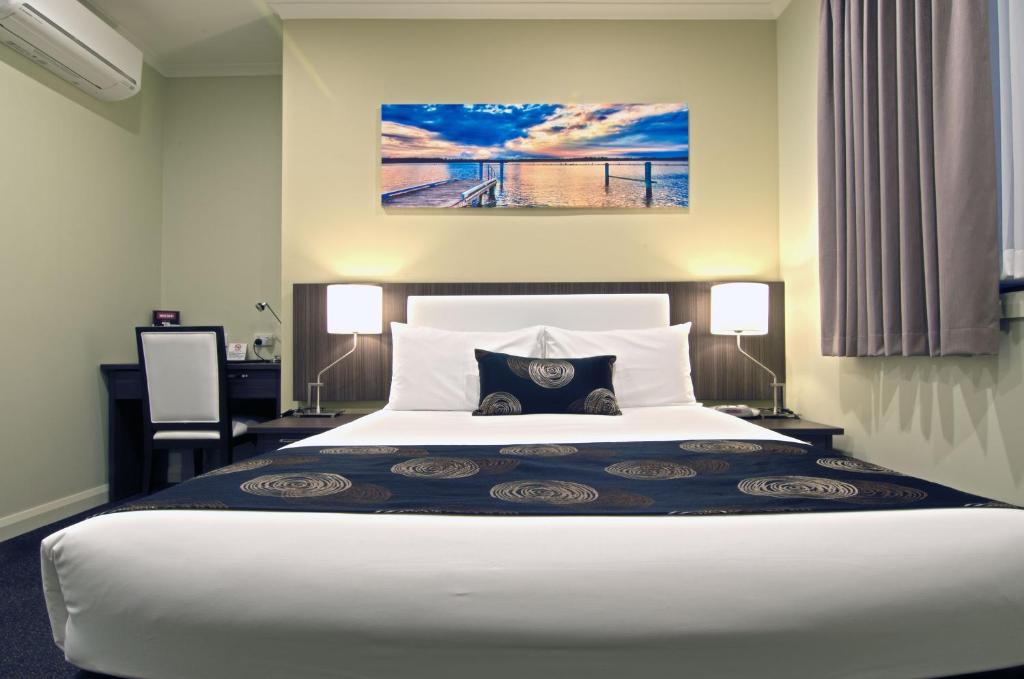 墨尔本帕克斯奎尔汽车旅馆和服务式公寓的卧室配有一张白色大床和一张书桌