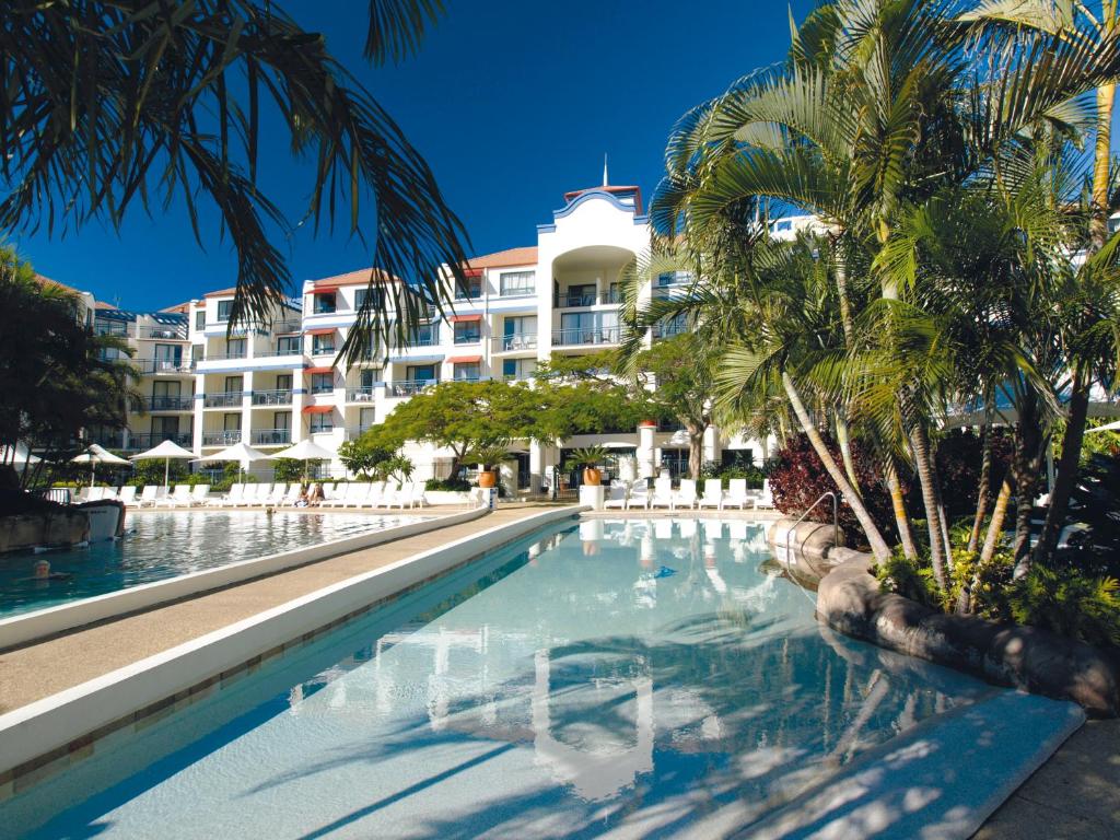 黄金海岸Oaks Gold Coast Calypso Plaza Suites的棕榈树建筑前的游泳池