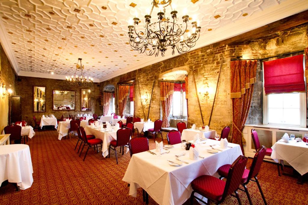 格兰瑟姆Angel and Royal Hotel的餐厅配有白色的桌椅和吊灯