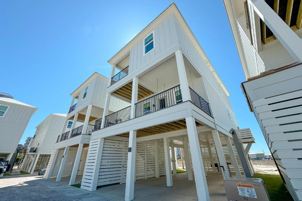 格尔夫海岸The Hangout House Relaxed 4BR Luxury, 3 King Suites, Walk to Beach, Pet Friendly的海滩上一座带阳台的大型白色建筑