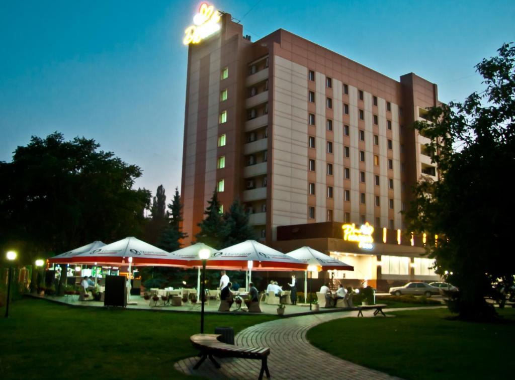 克里沃罗格德鲁日巴酒店的大楼前有桌子和遮阳伞的酒店