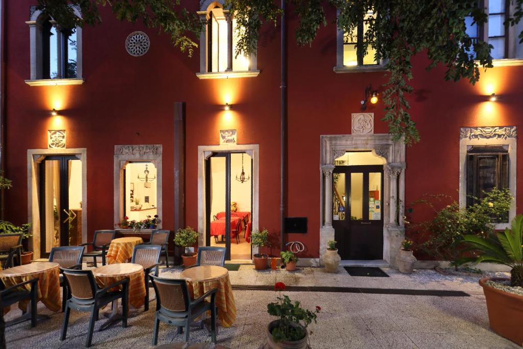 陶尔米纳阿斯托利亚别墅酒店的一间位于红色建筑前的餐厅,配有桌椅