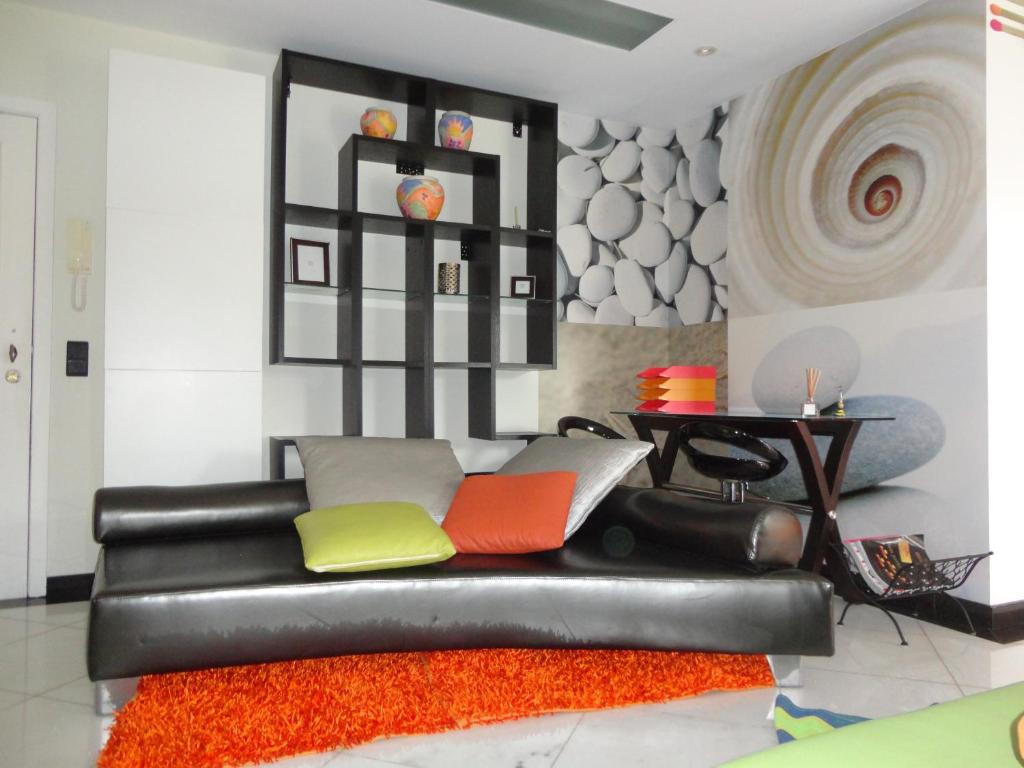 卡尼索Apartamento Raio de Sol的客厅配有黑色皮革沙发及色彩缤纷的枕头