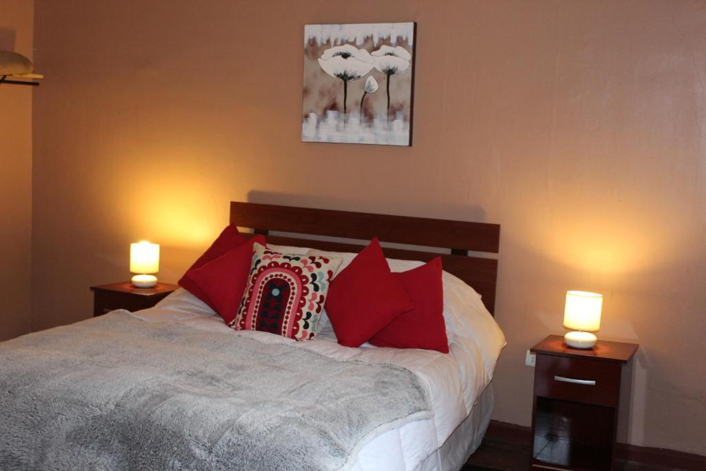 圣何塞德迈波Casa En La Precordillera的一间卧室配有一张带红色枕头和两个灯的床。