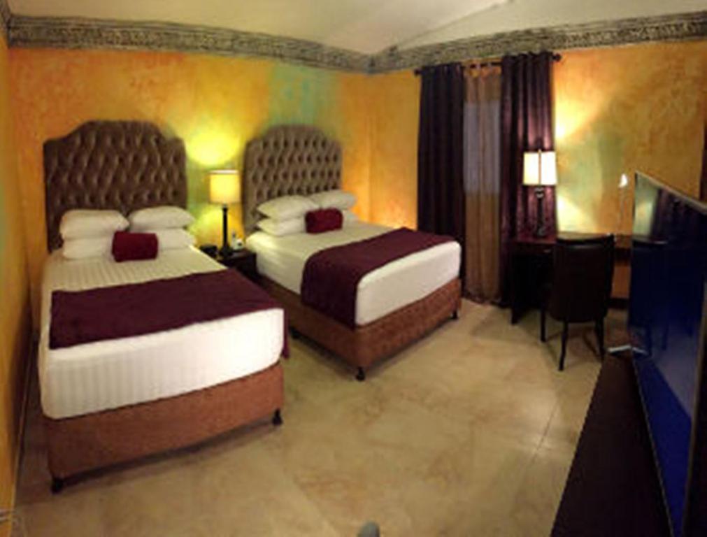 危地马拉Antigua Inn Hotel的酒店客房设有两张床和电视。