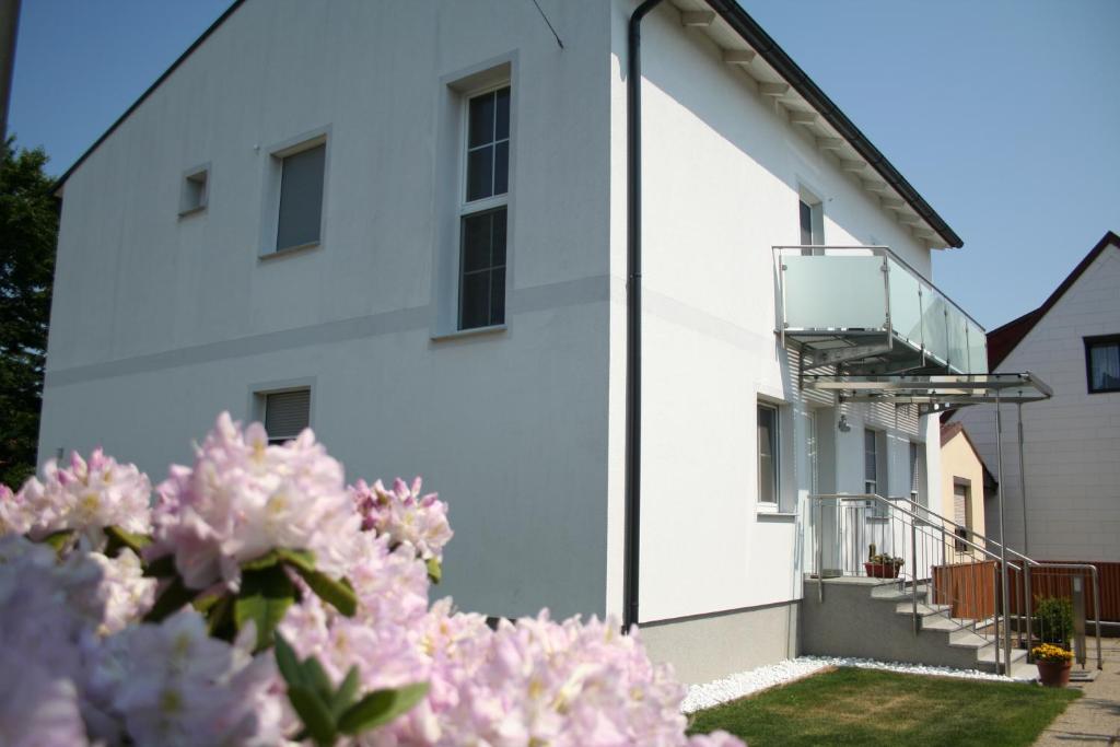 拉斯特Gästehaus Karassowitsch的带阳台和粉红色鲜花的白色建筑