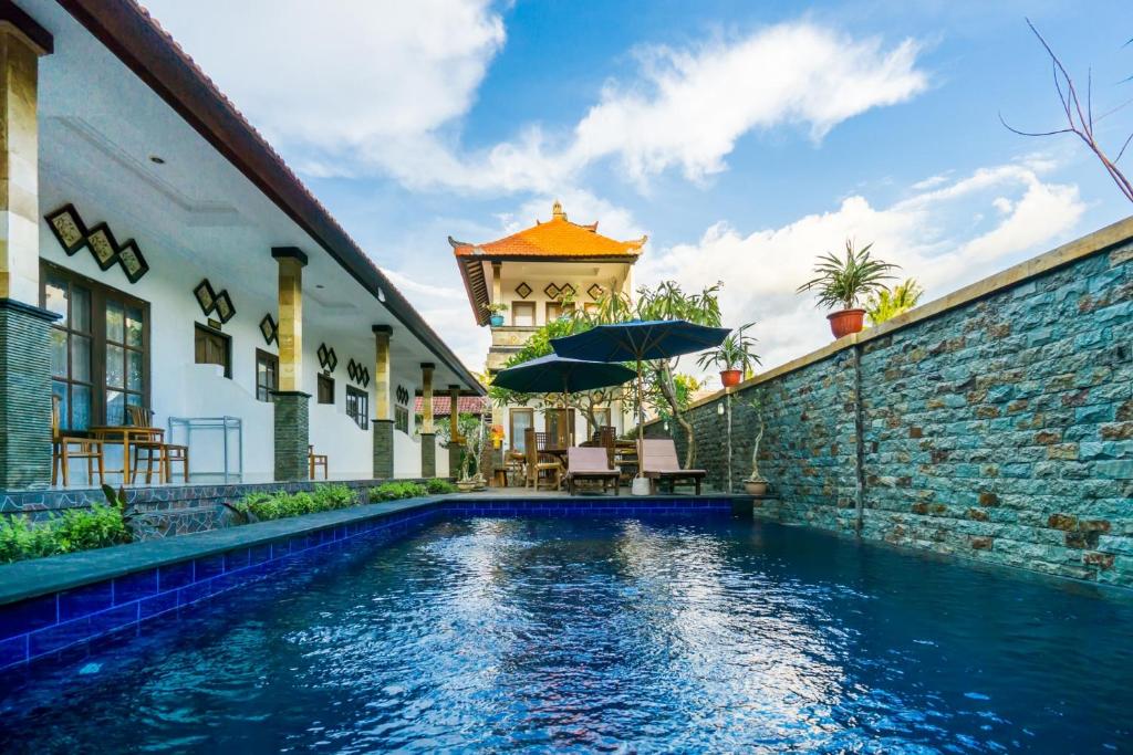 蓝梦岛Widia Homestay Nusa Lembongan的砖墙旁的一座房子,设有游泳池