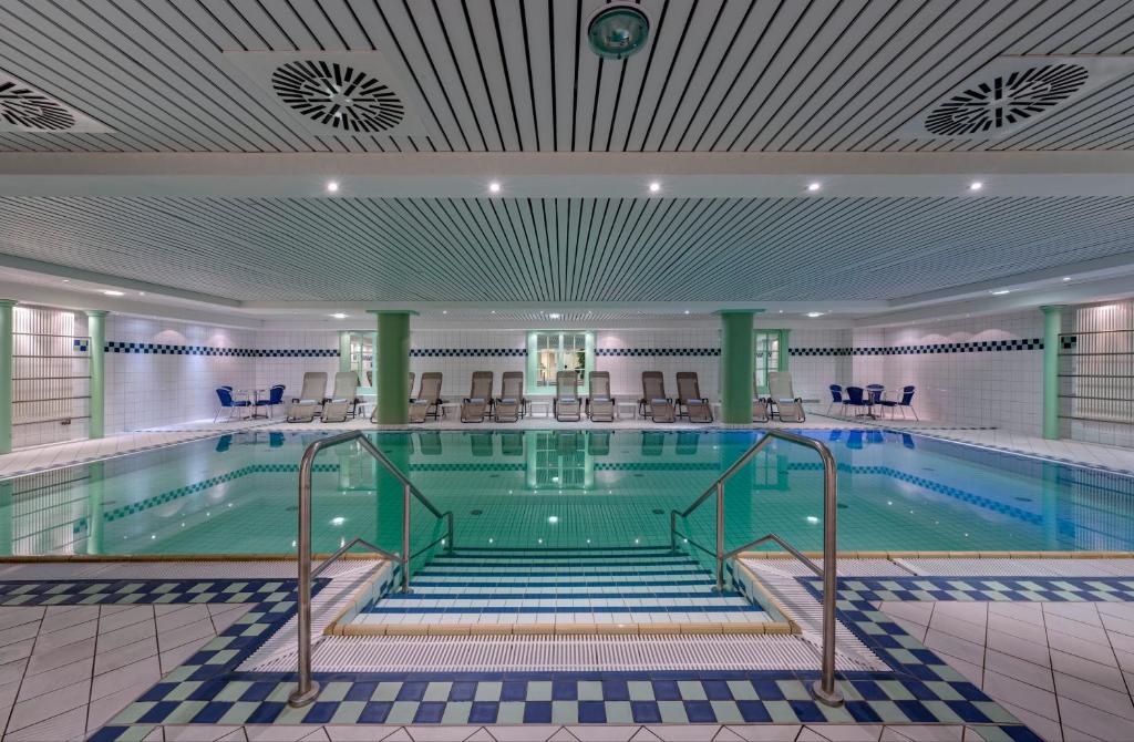 奥斯赛拜-屈隆斯博恩海蓝玉酒店的大楼内带椅子的大型游泳池