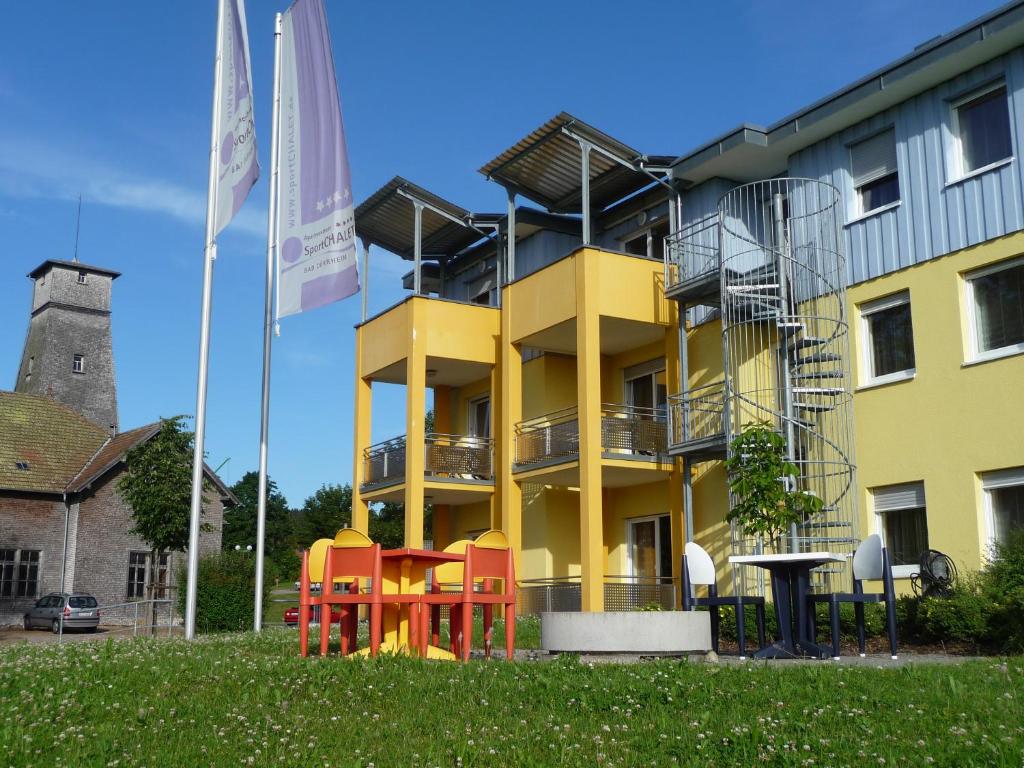 巴特迪尔海姆运动小屋公寓的前面有五颜六色椅子的黄色建筑