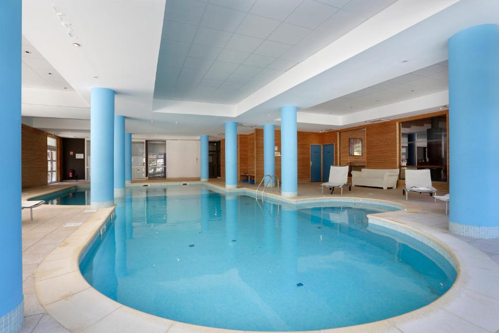 拉富Vacancéole - Les Chalets du Verdon的蓝色柱子的酒店的大型游泳池