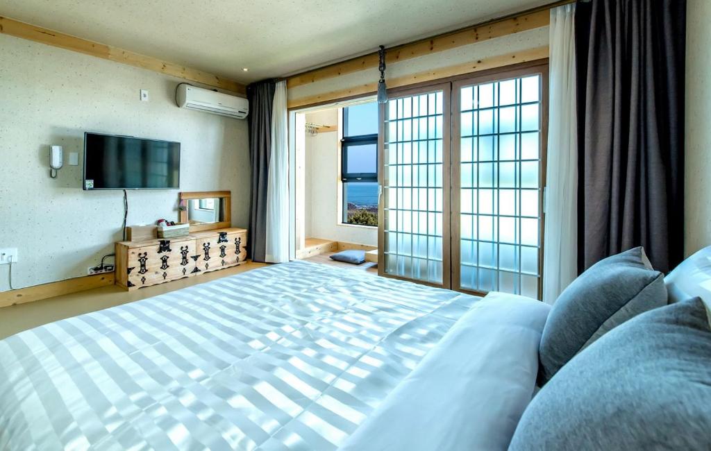 西归浦市巴达丸度假屋的一间卧室设有一张大床和一个大窗户