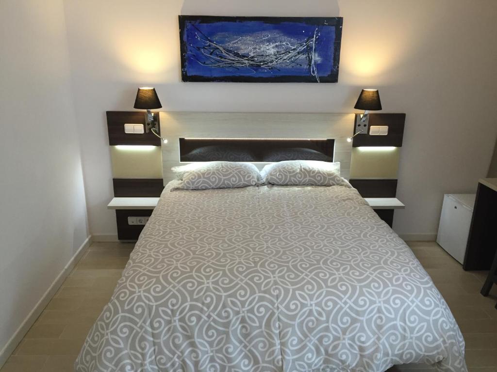 阿尔考空H天际线旅馆的一间卧室配有一张带两盏灯的床,墙上挂有一幅画